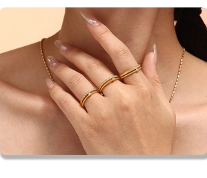 Detail of stacked gold zircon rings with beaded edges and pavé diamonds on model