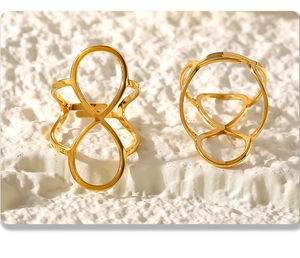 Detail van gepolijste gouden oneindigheid ringen op een witte gestructureerde ondergrond