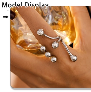 Detail of silver irregular bead open ring worn by model holding a glass