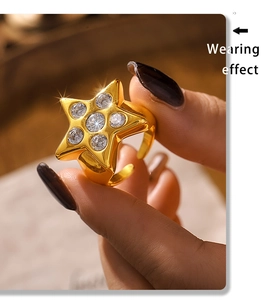 Detalle macro de un anillo de estrella dorado con circonitas en la mano