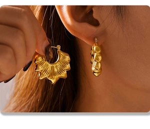 Primer plano de pendientes de aro bañados en oro de 18K con superficie ondulada plisada