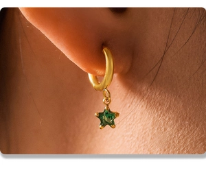 Macro shot of 18K gold plated hoop earring with a green star-shaped glass charm