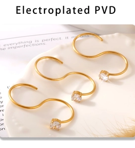 Détail de trois boucles d'oreilles S dorées avec placage PVD et pierres de zircone rondes