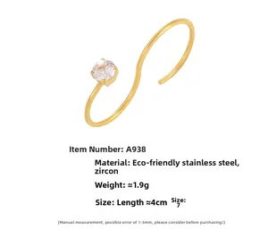 Détails d'une bague dorée en forme de S avec sertissage de zircon et acier inoxydable poli