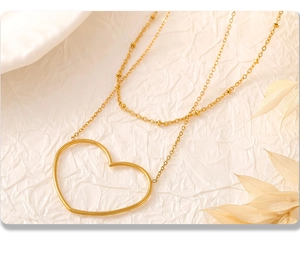 Dettaglio collana a doppio strato placcata oro 18K con ciondolo a cuore su carta beige