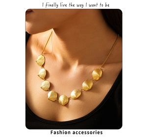 Nahaufnahme einer goldenen Muschelkette mit acht strukturierten Anhängern an einem Model