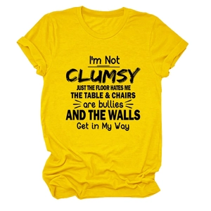 Close-up of yellow cotton T-shirt with I'M NOT CLUMSY JUST black graphic text print