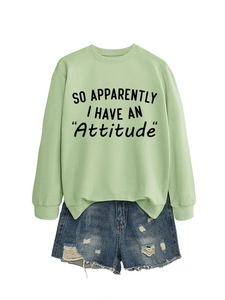 Detail of mint green sweatshirt with 'Attitude' text and distressed denim shorts