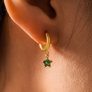 Elegant 18K gold-plated star drop earring with vibrant green gemstone on a female model