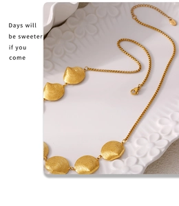 Detail einer goldenen Muschelkette mit Radialtextur auf einer weißen Reliefplatte
