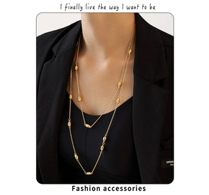 Detailed view of layered gold double-strand beaded necklace on black sweater