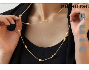 Close-up of a double-layered gold stainless steel necklace with oval bead details