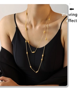Detail of gold double-layered sweater necklace with irregular beads on model
