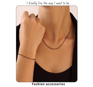 Détail de l'ensemble collier et bracelet dorés à perles avec des perles noires minimalistes