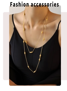 Close-up of a double-layered gold beaded necklace worn over a black top for women