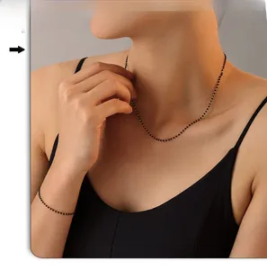 Ensemble collier et bracelet en chaîne dorée avec perles noires porté par un modèle