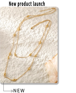Detail of 18K gold-plated double-layer necklace with oval bead accents on white stone