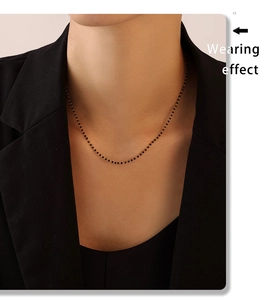 Effet porté d'un collier en chaîne dorée minimaliste avec petites perles noires