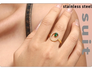 Detail of a gold stainless steel ring with green oval gemstone and pavé diamonds