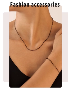 Ensemble collier et bracelet minimaliste en chaîne dorée avec perles noires sur un mannequin