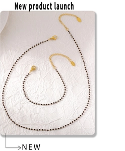 Détail du collier en acier inoxydable doré avec perles noires et étiquette S.Steel