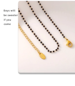 Détail du fermoir mousqueton réglable et de l'étiquette en acier sur collier de perles