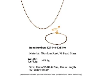 Détail de l'ensemble collier et bracelet en acier titane doré avec perles de verre noires
