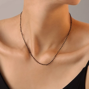 Collier minimaliste en or avec perles noires sur chaîne fine porté par un mannequin femme
