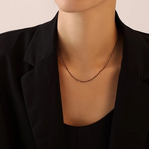 Collier élégant en titane doré avec perles noires sur un mannequin en costume noir