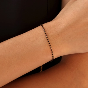 Bracelet minimaliste en chaîne dorée avec perles noires au poignet en acier titane
