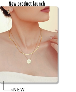 Detalle del collar dorado de doble capa con trébol y pendientes con gemas de colores
