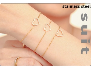 Vue macro de trois bracelets cœur en or avec zircons incrustés et texture acier inoxydable