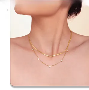 Detailed view of layered gold star pendant necklace and snake chain on neck