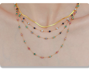 Detalle de collar de capas con cadena de serpiente dorada y cuentas de colores boho