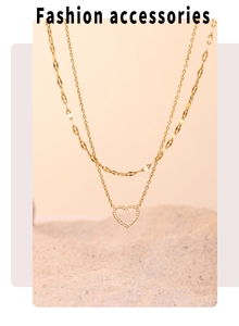 Gros plan sur collier double chaîne dorée avec pendentif cœur évidé et cristaux