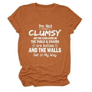 Detail of burnt orange crew neck T-shirt featuring I'M NOT CLUMSY JUST white slogan print