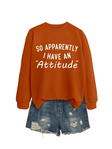 Orange crewneck sweatshirt with 'Attitude' text and distressed denim shorts flat lay