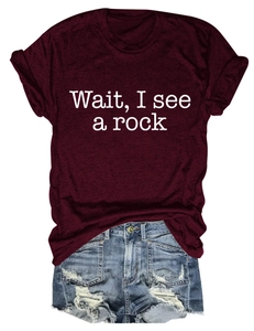 Flat lay of a burgundy 'Wait, I see a rock' T-shirt and distressed light blue denim shorts