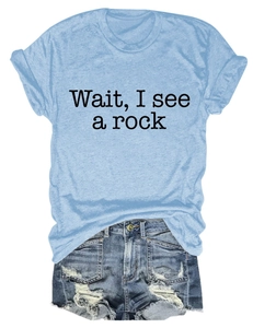 Flat lay of light blue T-shirt with 'Wait, I see a rock' text and ripped denim shorts