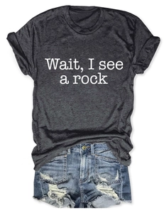 Detail view of dark grey T-shirt with 'Wait, I see a rock' text and denim shorts