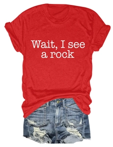 Flat lay of a red cotton t-shirt with 'Wait, I see a rock' text and ripped denim shorts