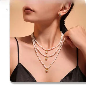 Gros plan du collier de perles à trois rangs avec pendentifs dorés et boucles d'oreilles