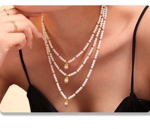 Détail d'un collier de perles à trois rangs avec billes dorées et pendentifs gouttes
