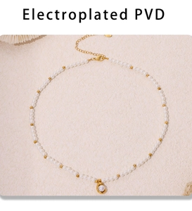 Détail d'un collier de perles avec perles dorées PVD et pendentif ovale sur fond beige