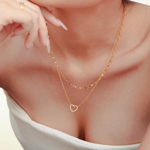 Collier double couche doré avec pendentif cœur pavé de zircons porté par un mannequin