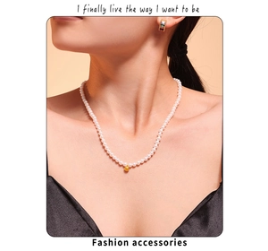 Close-up of Baroque pearl necklace with gold sphere pendant on a model's neck