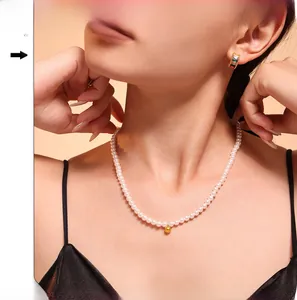 Close-up of elegant baroque pearl necklace with gold sphere pendant and colorful gem earrings