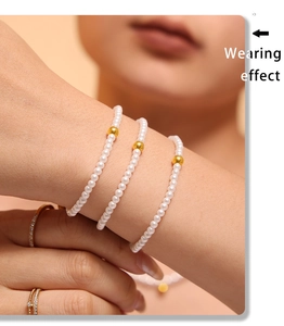 Detailed shot of pearl bracelets with golden beads and sparkling rings on model hand
