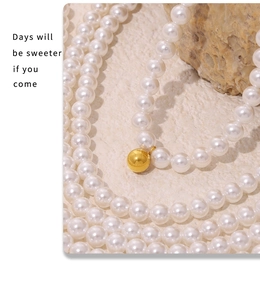Detailed close-up of baroque pearl necklace with a polished gold ball pendant