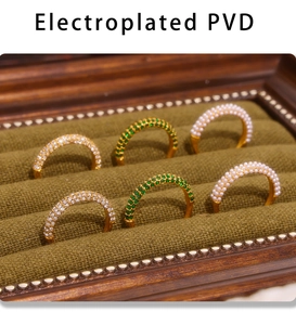 Détail de bagues plaquées or PVD avec cristaux verts, perles et diamants blancs pavés